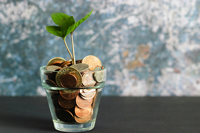 Stacks of coins with small green sprouts, suggesting savings and investments growing over time through compound interest